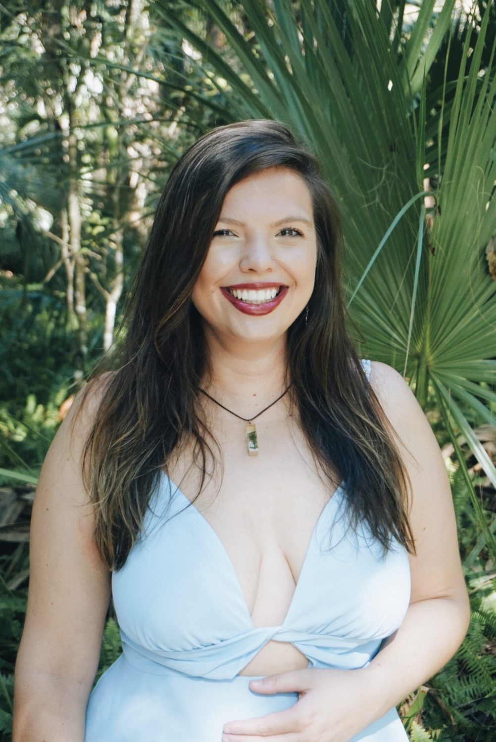 Mandy Roux, somatic trauma counselor in Orlando Florida, smiling in front of green palm fronds